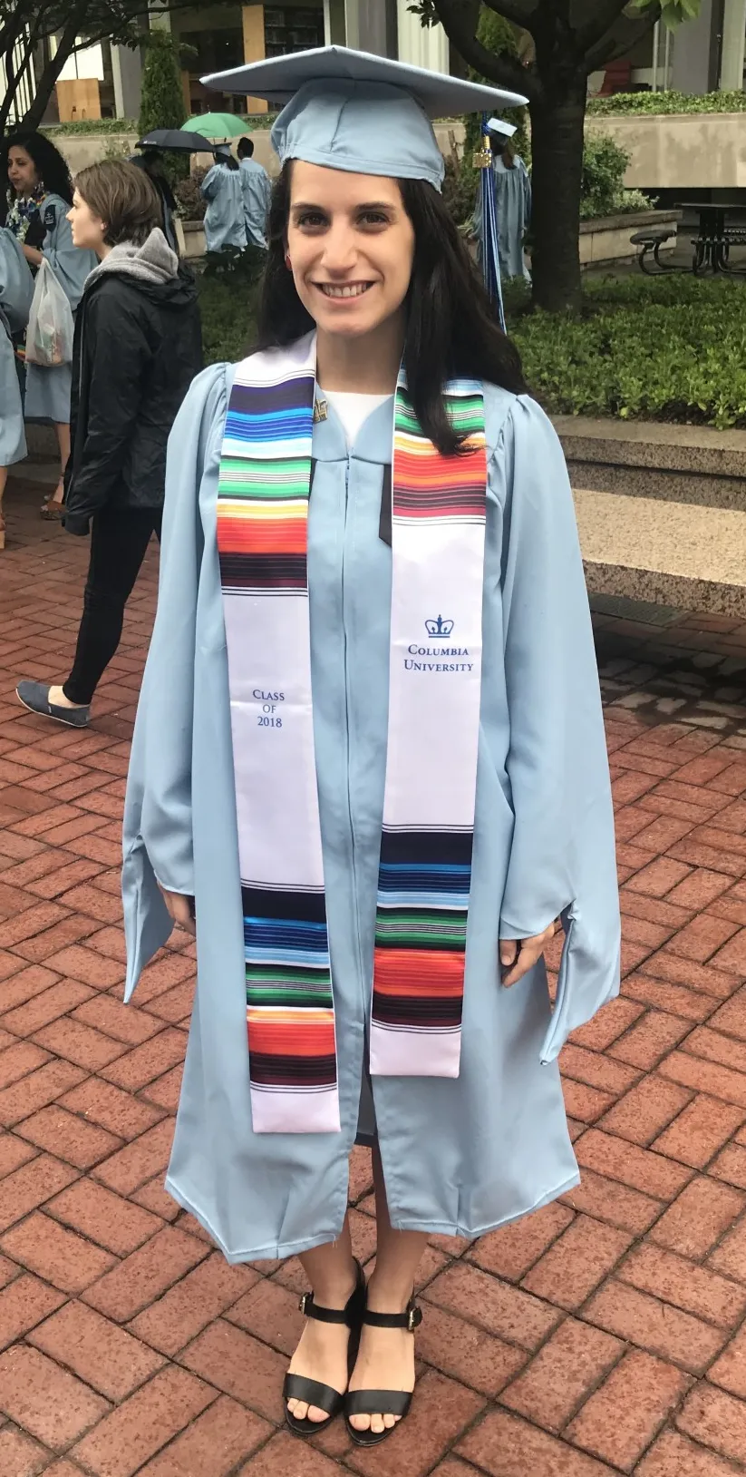 Adriana standing in her graduation cap and gown.