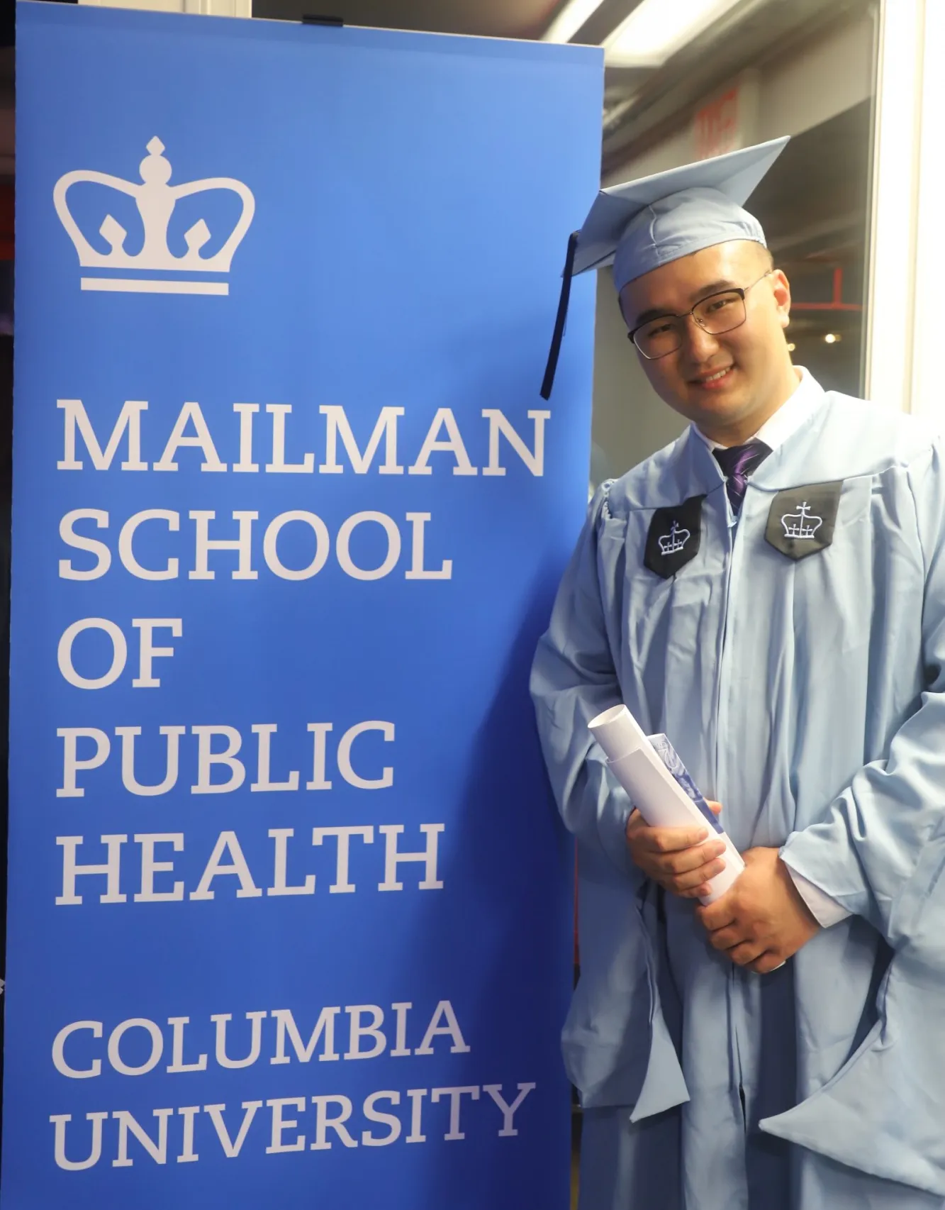 Wenhan standing in his graduation cap and gown